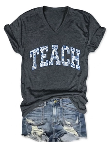 Dettaglio della t-shirt grigio scuro con scollo a V, stampa TEACH e pantaloncini