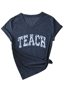 Dettaglio di maglietta blu scollo a V con scritte floreali TEACH e orlo annodato