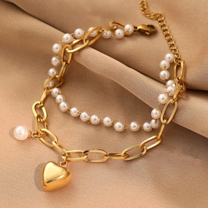 Double-layer gold necklace with heart pendant and faux pearls on beige silk fabric