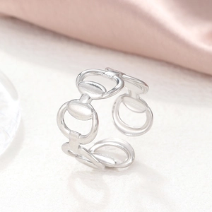 Macro shot of silver horsebit chain ring with polished finish on soft pink silk