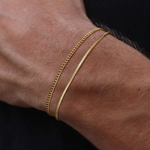 Detail of double-layer gold stainless steel bracelets featuring flat snake and curb chain