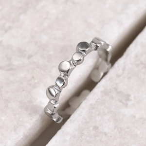 Macro shot of silver ring with irregular polka dot texture on natural stone