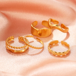 Minimalist wavy gold titanium steel rings set on elegant peach satin fabric background
