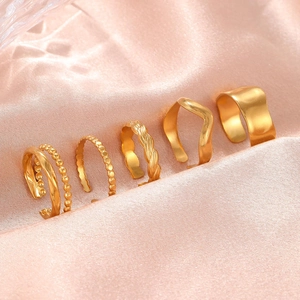 Set of five gold wave and twisted stainless steel rings on pink silk background