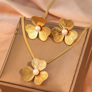 Golden flower jewelry set with pearl necklace and stud earrings on silk background