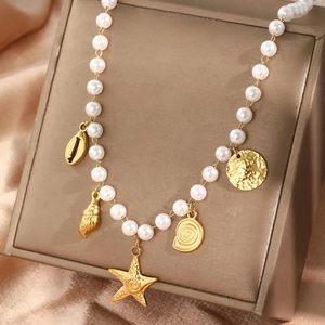 Elegante Perlenkette mit goldenen Seestern- und Muschelanhängern auf Lederständer