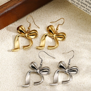 Elegant bow-shaped earrings in polished gold and silver finishes on a vintage background