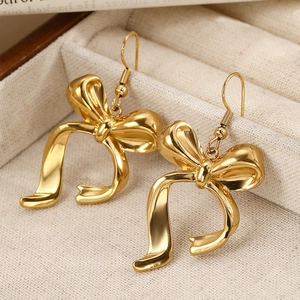 Elegant gold bow earrings with a polished finish displayed on a beige jewelry box