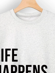 Detail of grey crewneck sweatshirt featuring black LIFE HAPPENS text on a wooden hanger