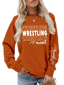 Detail of orange sweatshirt featuring arm print and wrestling heart design on sleeve
