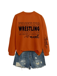 Detail view of orange wrestling aunt sweatshirt and denim shorts set laid flat