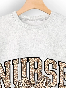 Détail d'un sweat gris montrant l'imprimé NURSE avec motif léopard et design de nœud