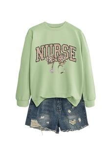 Détail du sweat vert sauge avec motif d'infirmière léopard et short en jean bleu
