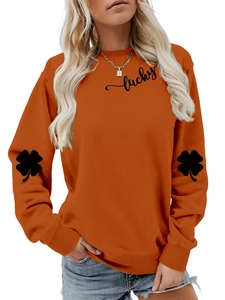 Close-up of lucky letter print and clover pattern on orange women's sweatshirt sleeve