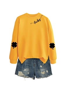Detail of yellow lucky sweatshirt with clover sleeve print and ripped denim shorts