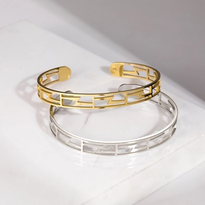 Détail de bracelets ajourés en C avec motifs géométriques éclair en finitions or et argent