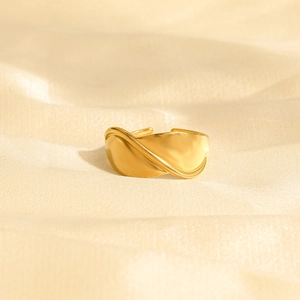 Bague ajustable en acier doré au design de feuille torsadée sur tissu beige