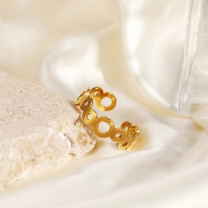 Macro shot of gold geometric open ring with hollow ring design on stone and silk