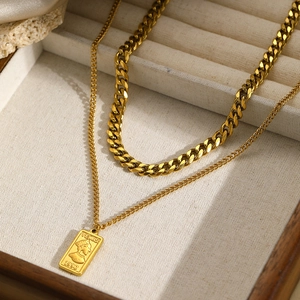 Double-layered gold Cuban chain necklace featuring a vintage Venus pendant on beige tray
