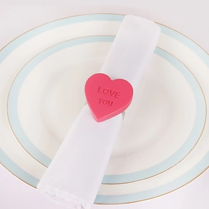 Rosa Herz-Serviettenring mit LOVE YOU Gravur auf einer weißen Stoffserviette