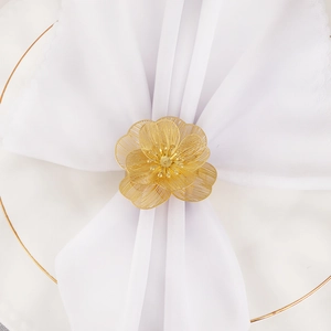Elegant gold mesh flower napkin ring on white plate for wedding and festive table decor