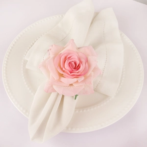 Pink fabric rose napkin ring on a white plate for elegant wedding table decor