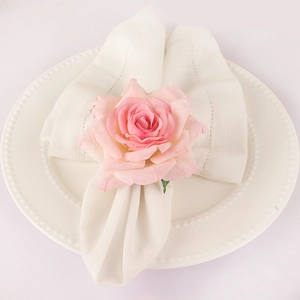 Pink handmade silk rose napkin ring set on a white lace napkin and pearl-edged plate