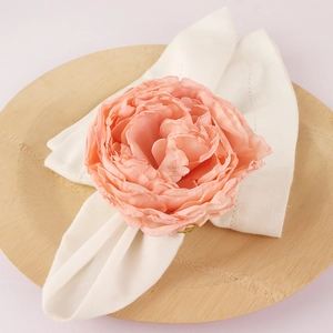 Pink peony flower napkin ring with layered silk petals on a white cotton napkin