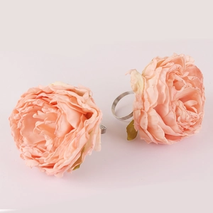 Close-up of pink peony floral napkin rings with elegant satin petals and silver metal band