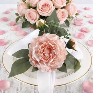 Servilletero artesanal de rosa rosa claro con hojas verdes sobre vajilla elegante