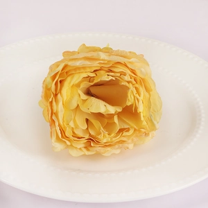 Detailed top view of a handmade yellow silk flower napkin ring on a white ceramic plate