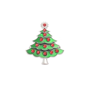 Macro detail of Christmas tree napkin ring with green enamel and red crystal rhinestones