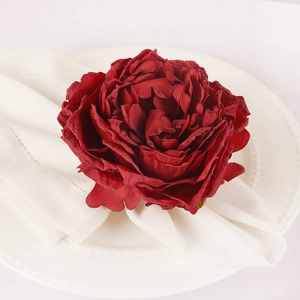Elegant deep red peony fabric napkin ring on white ceramic plate for table setting