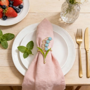 Detail of lily of the valley napkin ring on a pink fabric napkin and white plates