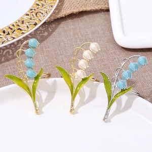 Close-up of enamel lily of the valley napkin rings on a white plate with rustic texture