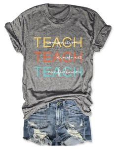 T-shirt gris anthracite Teach Compassion posé à plat avec un short en jean délavé