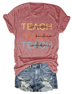 Détail de l'imprimé TEACH compassion sur un t-shirt rouge brique et short en jean