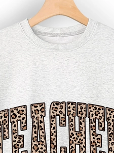 Detail of grey sweatshirt collar and Teacher slogan with leopard print textured lettering