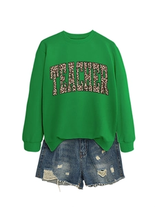 Flat lay of green crewneck sweatshirt with leopard print teacher text and denim shorts