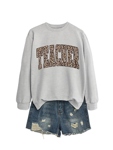 Detail of grey teacher sweatshirt with leopard print text and ripped denim shorts
