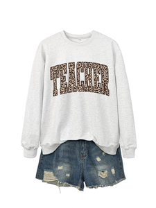 Close-up of gray crewneck sweatshirt with leopard print TEACHER lettering and denim shorts