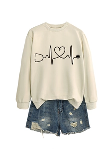 Flat lay detail of beige sweatshirt with heart stethoscope print and ripped denim shorts