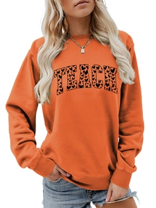 Detail of TEACH letters with black heart pattern on orange crewneck sweatshirt fabric