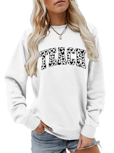 Close-up of white crewneck sweatshirt featuring a black heart-filled TEACH graphic