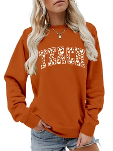 Detail of orange sweatshirt featuring white heart patterned TEACH lettering and crew neck