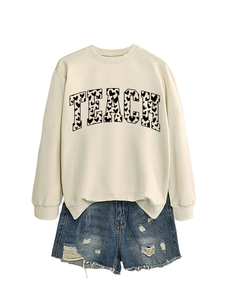 Detail of TEACH sweatshirt with heart pattern lettering and distressed denim shorts