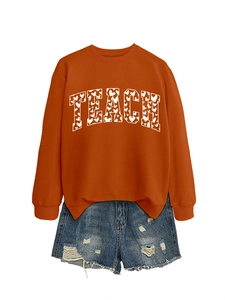 Close-up of orange Teach sweatshirt with heart pattern and distressed denim shorts