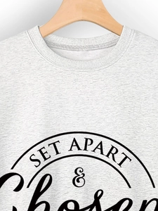 Detailed close-up of ribbed crewneck and SET APART & Chosen print on white cotton sweatshirt