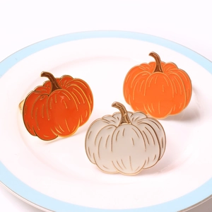 Close-up of enamel pumpkin napkin rings in orange and cream for Halloween table decor