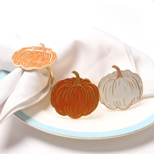 Detail of creative pumpkin napkin rings with gold trim on white napkins for table decor